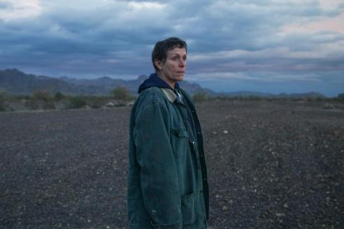 Frances McDormand wearing a work coat against a bleak landscape