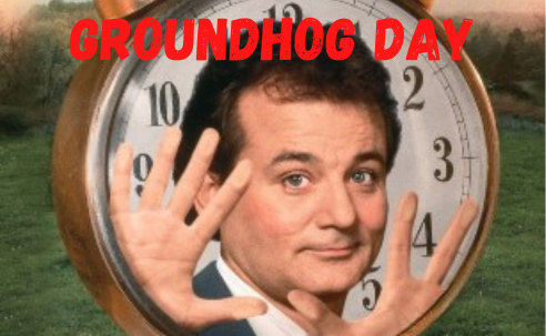 Groundhog Day Bill Murray holding hands up in front of large clock
